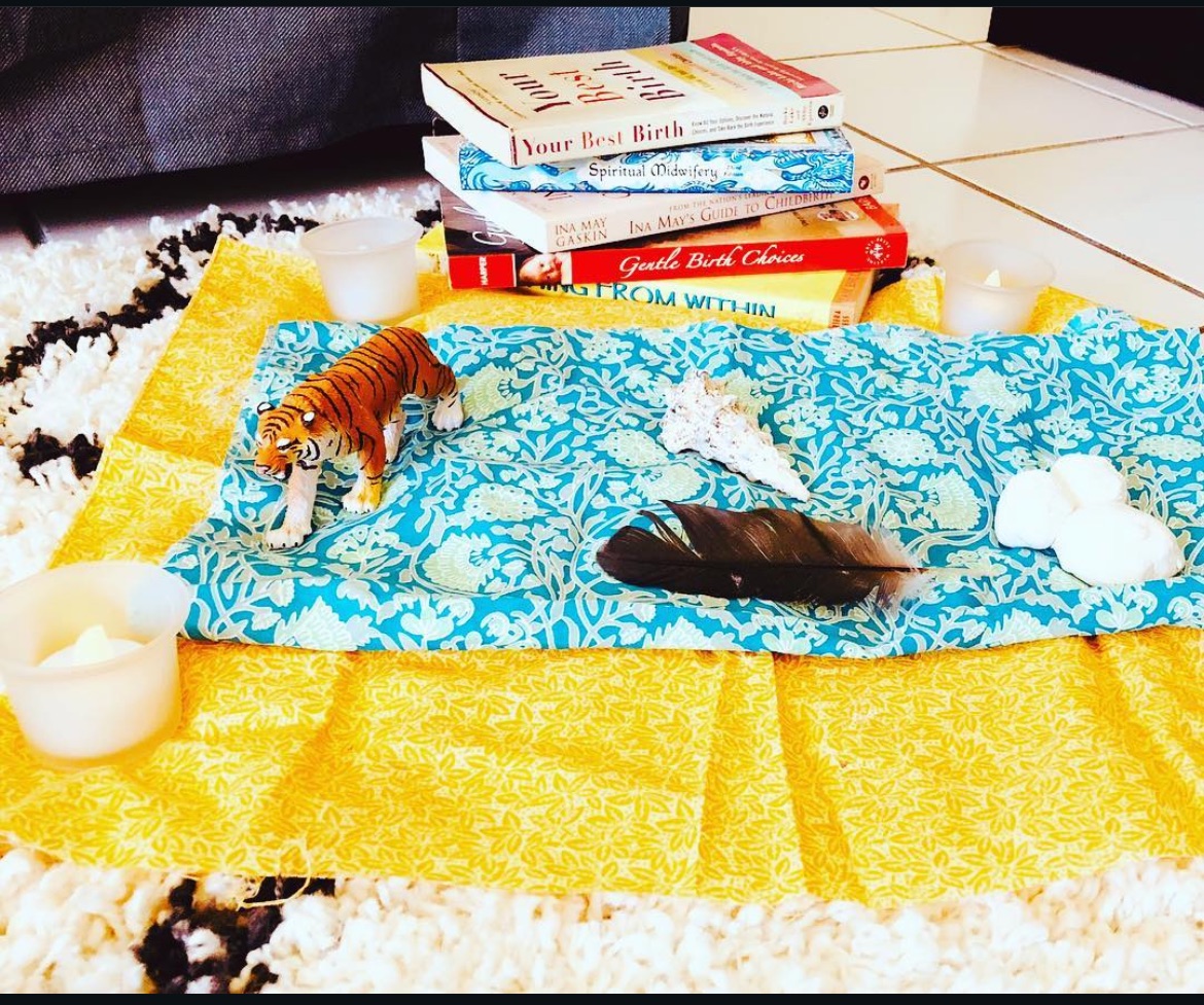 Birth preparation altar with candles, shells and birth books