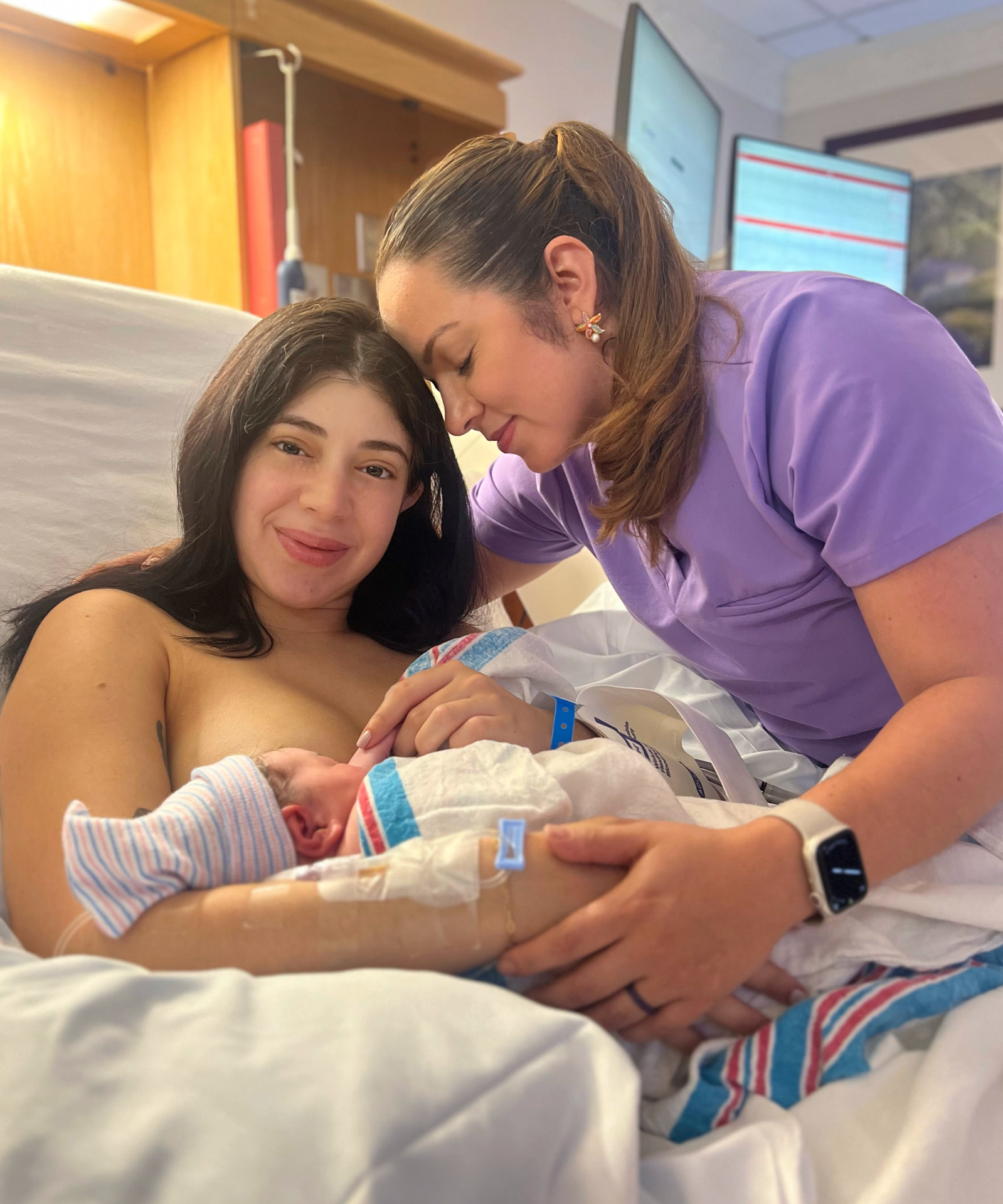 Doula embracing a new mother holding her newborn
