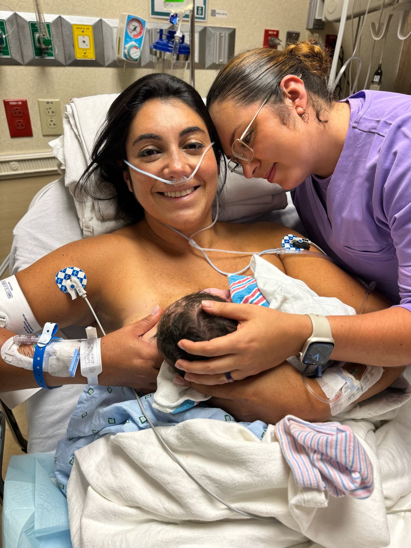 New mother smiling with her baby and doula beside her